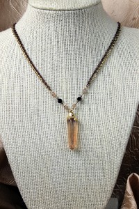 Peach quartz pendant on gold and black necklace